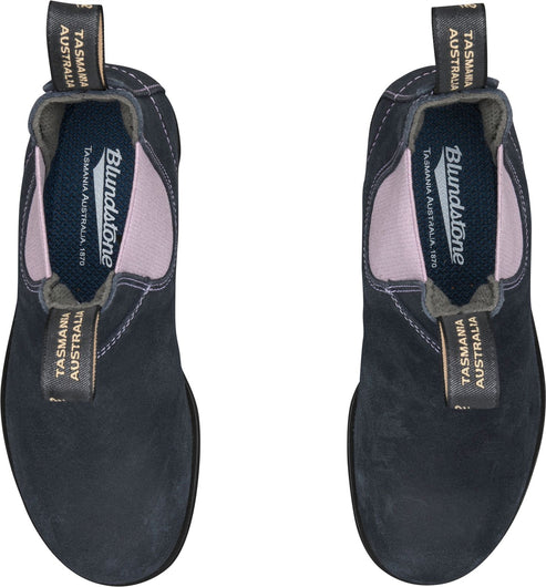 Two Blundstone boots are presented from a top-down perspective, showing their black suede exteriors, pink elastic side panels, and gray fabric pull tabs. The insides of the boots reveal a gray lining and insole with the text "Blundstone TASMANIA AUSTRALIA 1870" and "TASMANIA AUSTRALIA" displayed prominently.