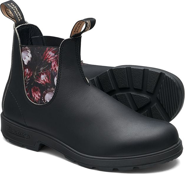 A pair of black leather Chelsea boots with floral accents around the ankle.