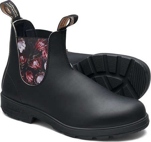 A pair of black leather Chelsea boots with floral accents around the ankle.