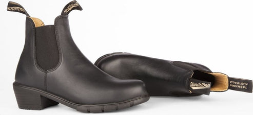 Two black leather heeled boots, one upright and the other lying on its side.