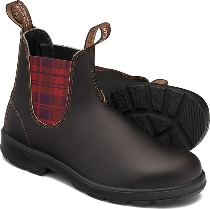 Two brown leather Chelsea boots with black soles, red plaid elastic side panels and pull loops.