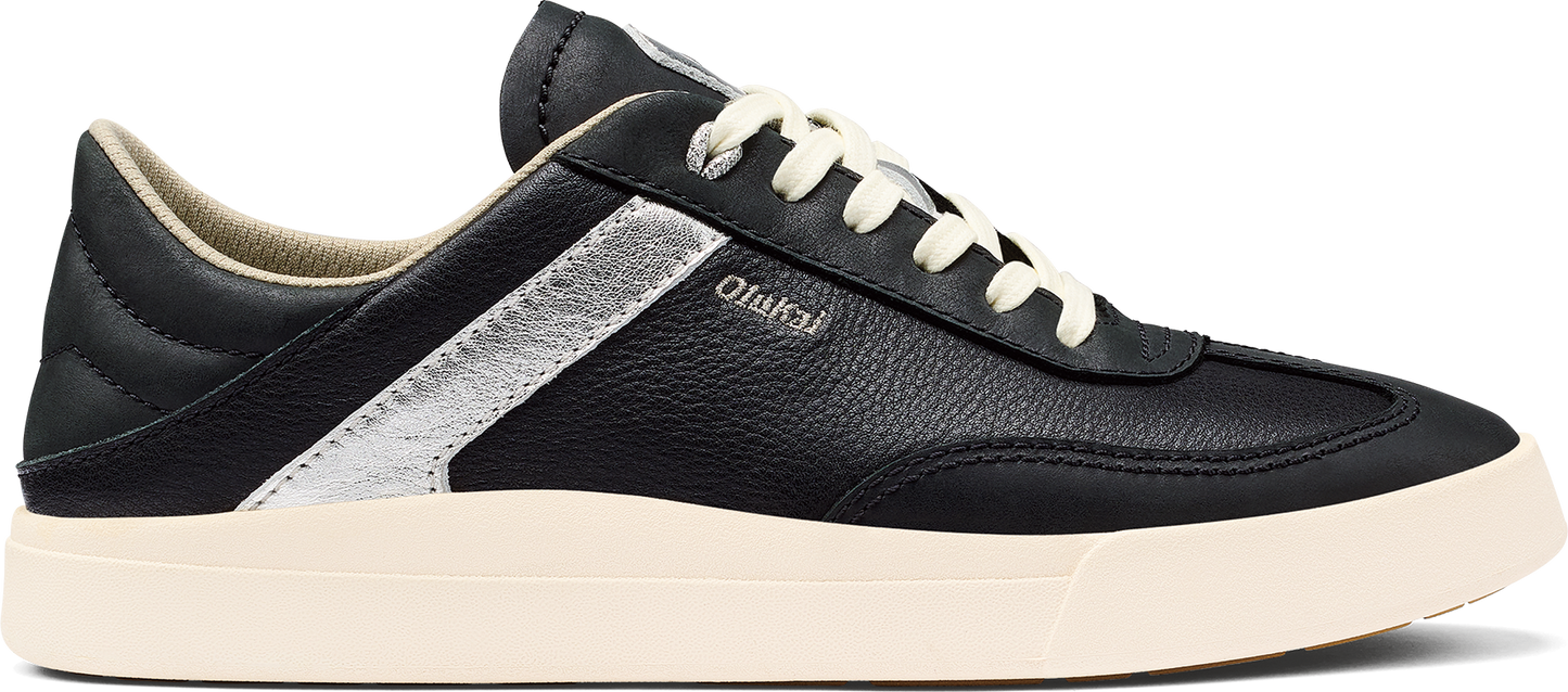 A black sneaker with white laces and a thick white sole.