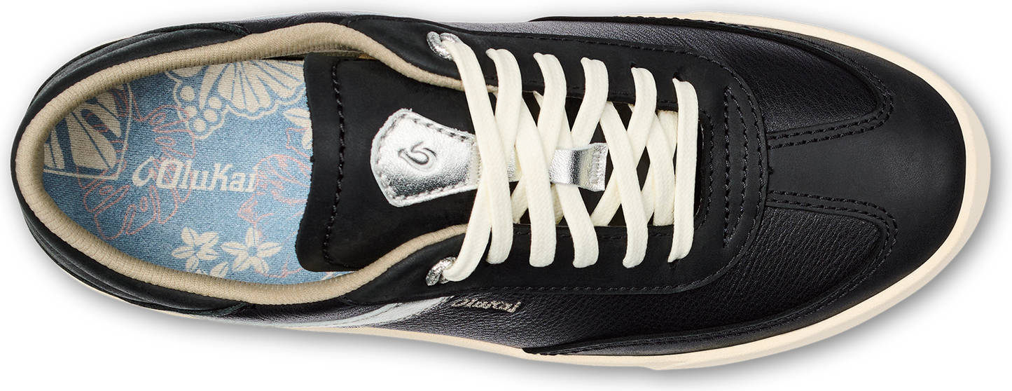 A black low-top sneaker with cream colored laces and the word "Olukai" on the side.