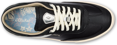 A black low-top sneaker with cream colored laces and the word "Olukai" on the side.