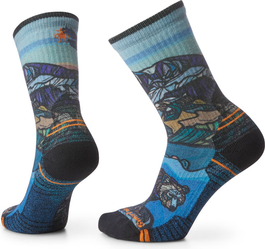 Two socks with a landscape design featuring mountains, water, and a bear.