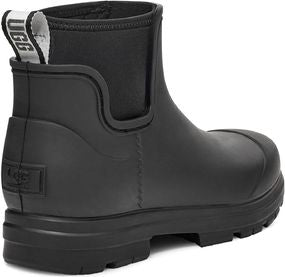 Black rubber ankle boot with elastic side panels, lug sole, and pull tab with white letters.