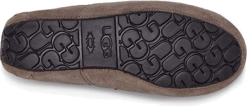 The sole of a moccasin slipper, revealing the UGG logo and a textured pattern.