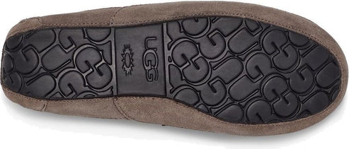 The sole of a moccasin slipper, revealing the UGG logo and a textured pattern.