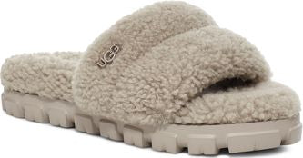 Beige, fuzzy slide with a lug sole, showcasing the UGG logo on the upper.