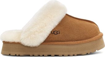 Tan suede clog slipper with cream-colored faux fur trim and flat platform sole; UGG logo on the side.